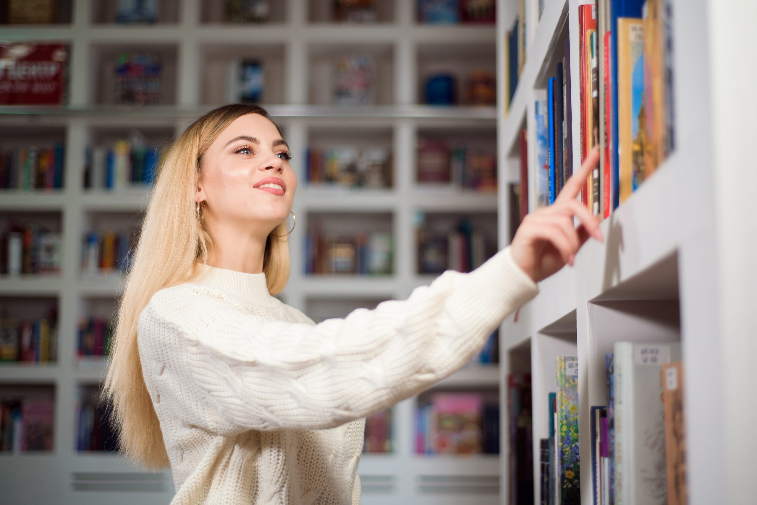 Studentka wybierająca książkę z półki